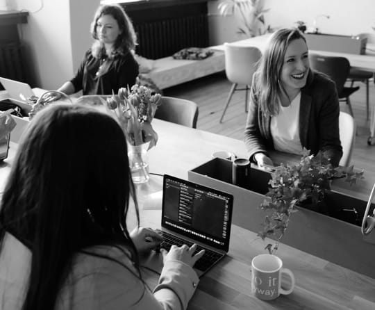 girls sitting in an office with laptops working